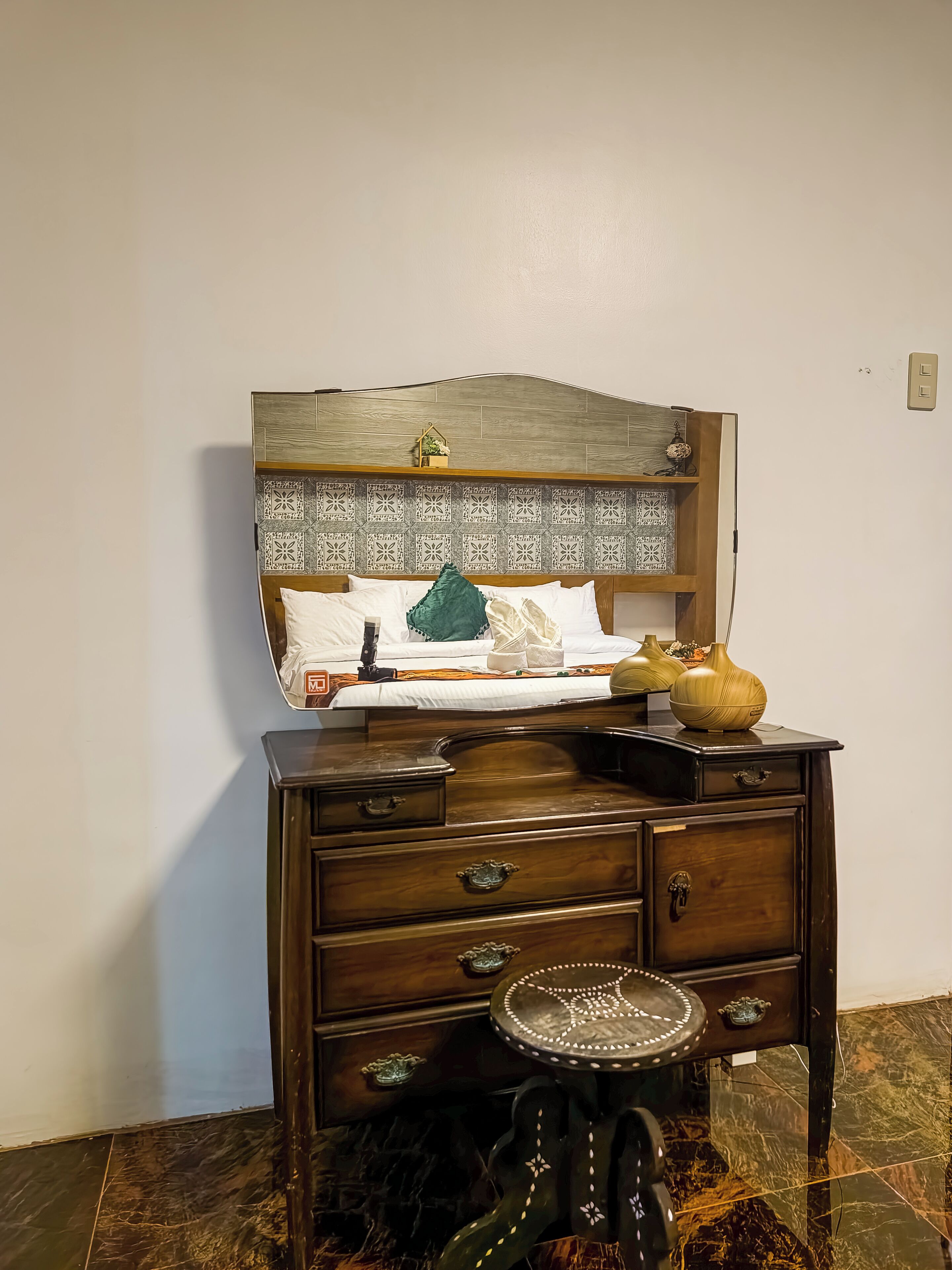 Une chambre à coucher avec un lit, une commode et un petit tabouret.