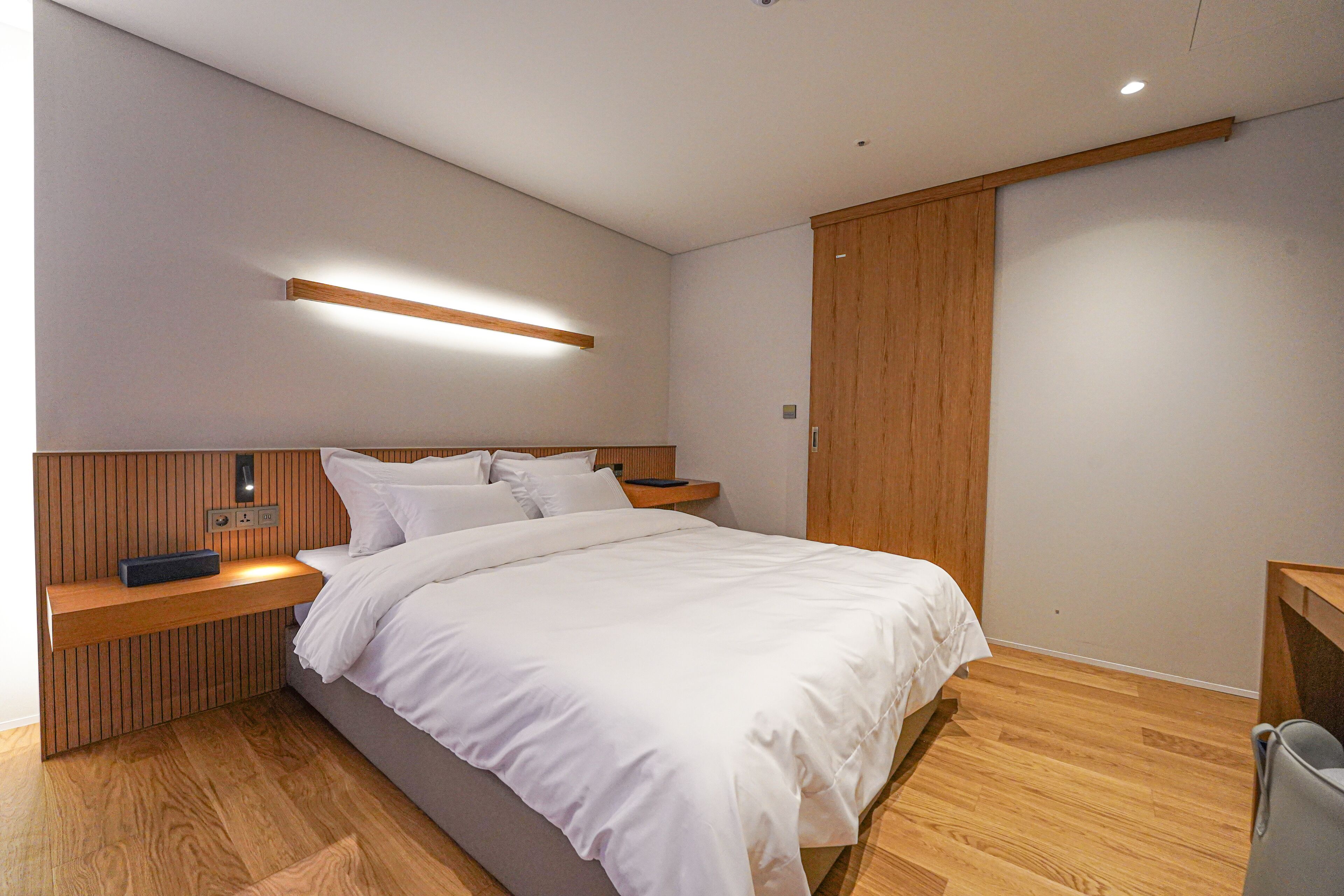 Una camera da letto moderna con una testiera in legno, un comodino con una lampada e un armadio.