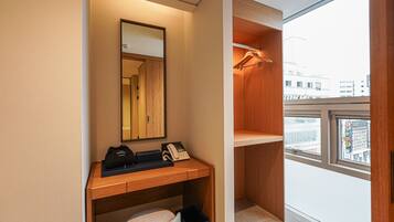 Una habitación de hotel moderna con un escritorio de madera, un teléfono, un bolso y un espejo.