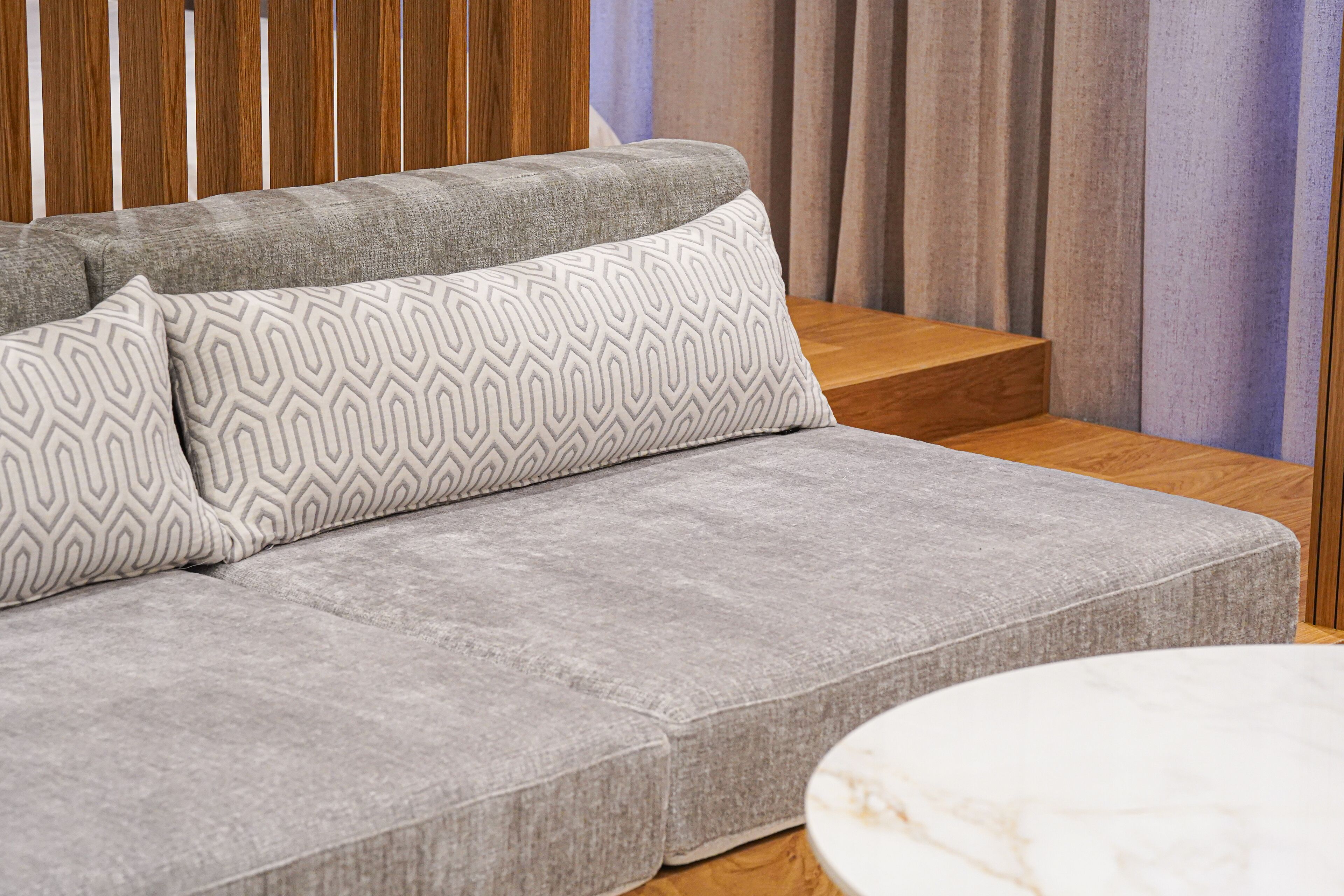 A grey sofa with patterned cushions and a wooden side table.