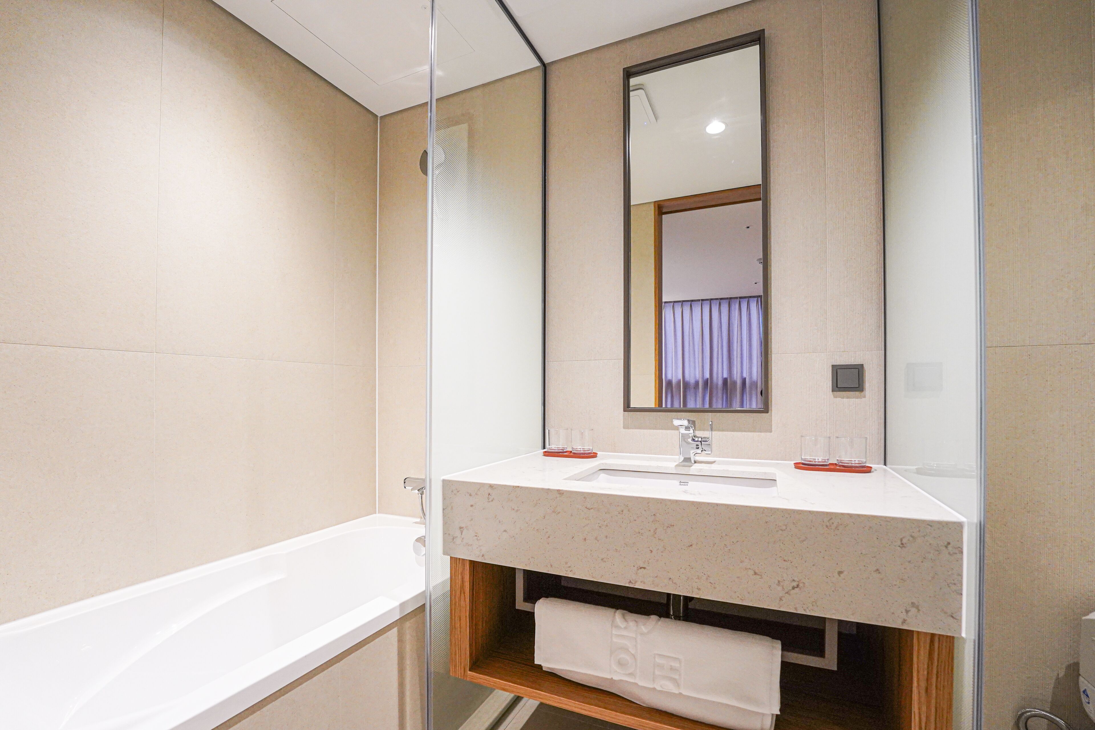 A modern bathroom with a white sink, mirror, and bathtub.