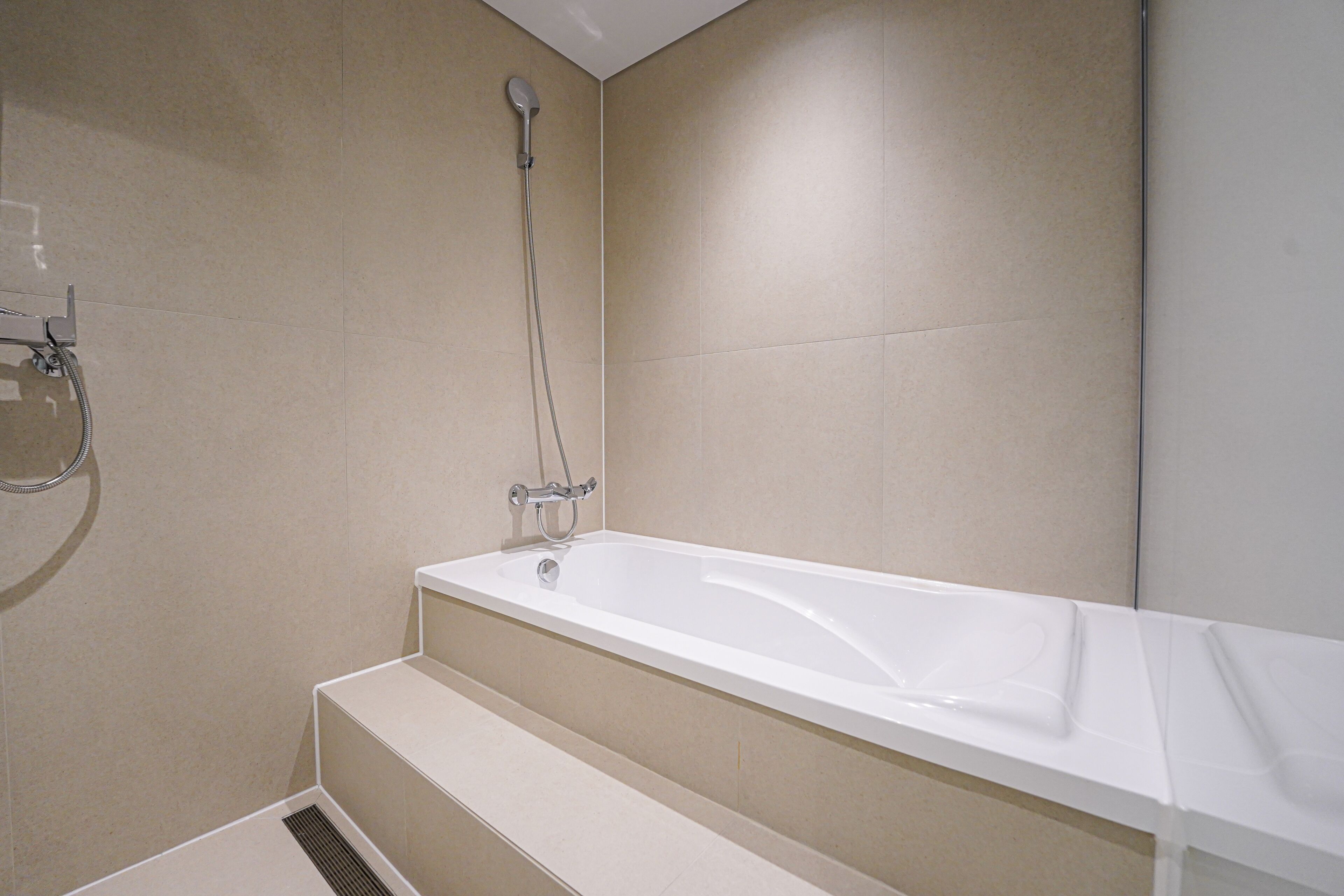 A modern bathroom with a bathtub, shower, and a step leading to the shower area.