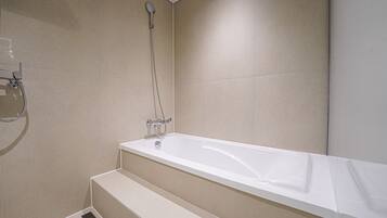 A modern bathroom with a bathtub, shower, and a step leading to the shower area.