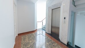 Een gang met een marmeren vloer, een deur en een lift.