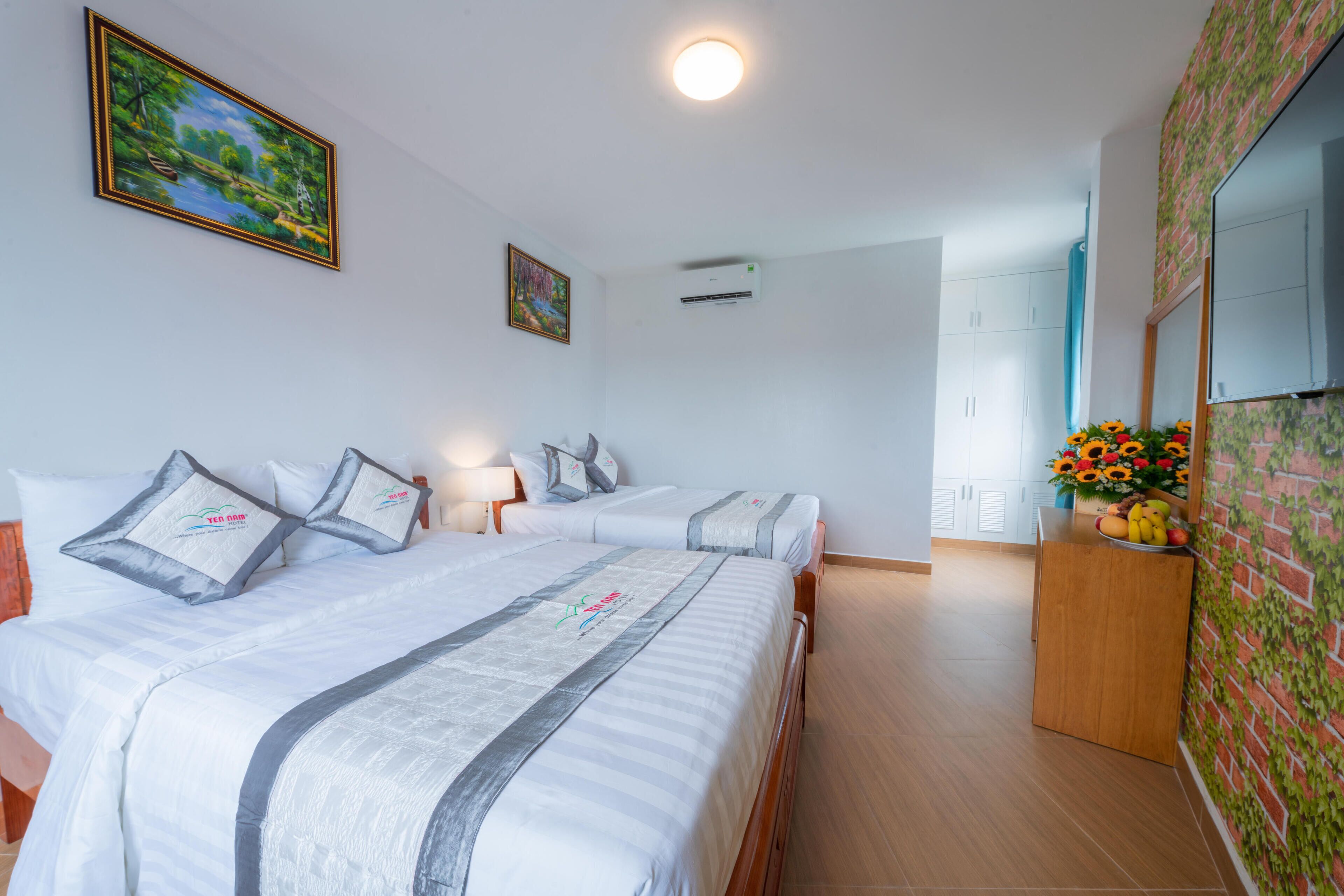 Una habitación de hotel con dos camas, un aparador de madera, un espejo y una pared con diseño floral.