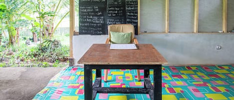 A room with a table and a chair, a chalkboard with menu items, and a sign with the logo 'OYO'.