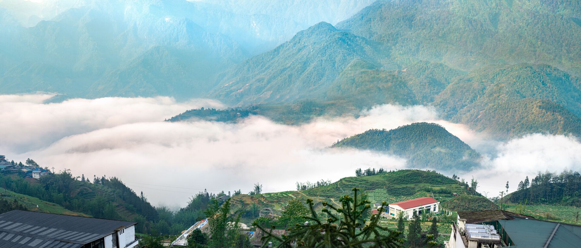 A mountainous landscape with a valley, houses, and a building with a red roof.