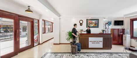 Zona de recepción de un hotel con mostrador, un reloj, un cuadro enmarcado y dispensador de agua.