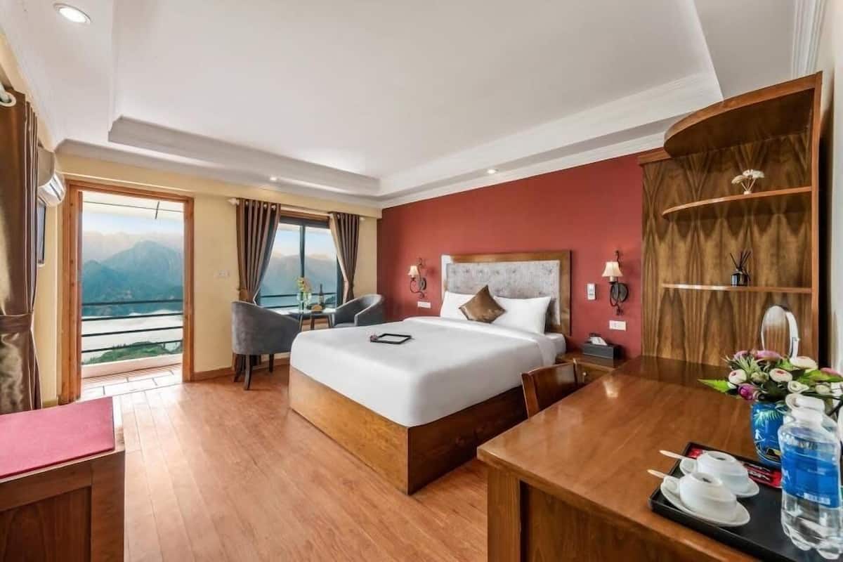 Une chambre d’hôtel avec un grand lit, un bureau et une vue sur les montagnes.
