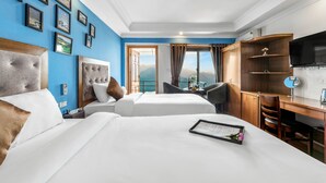 A hotel room with two beds, a desk, a TV, and a view of mountains. - Tiger Sapa Hotel (Sa Pa)