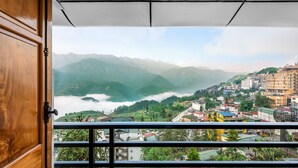 A balcony with a view of a mountainous landscape and a town below. - Tiger Sapa Hotel (Sa Pa)