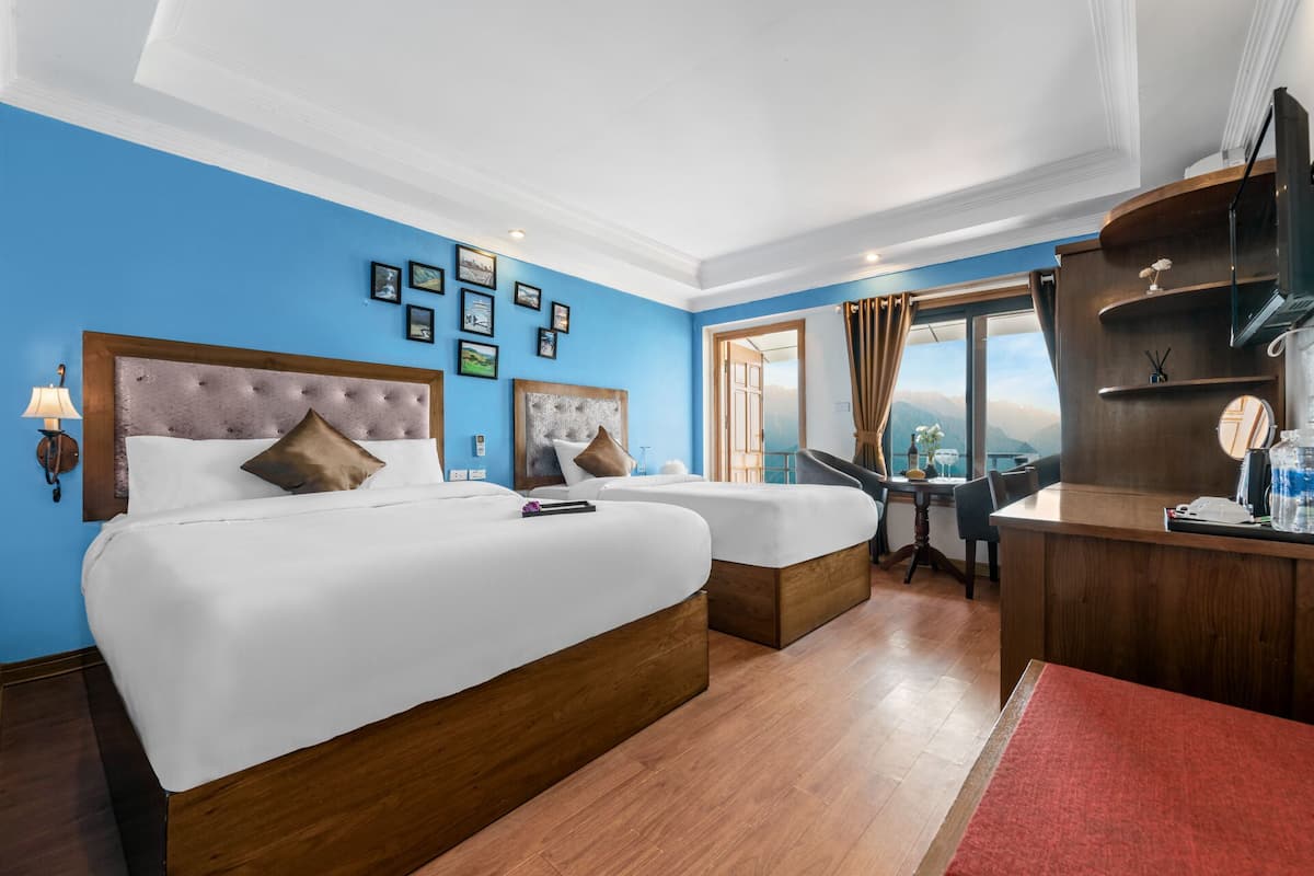 Une chambre d’hôtel avec deux lits, un bureau et une vue sur les montagnes.