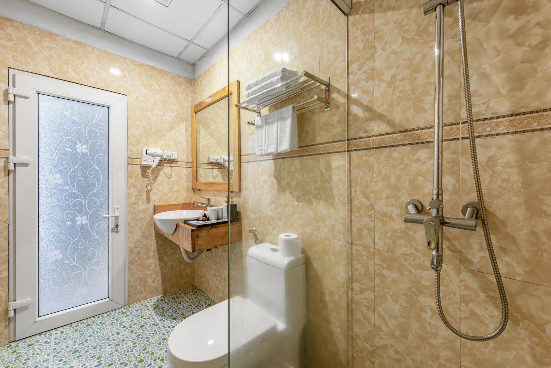 A bathroom with a toilet, sink, mirror, towel rack, and shower.