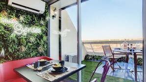 Un comedor moderno con una mesa para dos, un banco rojo y vistas de la ciudad a través de amplios ventanales.