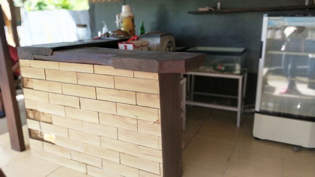 Un coin cuisine comprenant un comptoir en bois, un réfrigérateur et des étagères remplies de bouteilles.