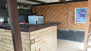 A bar area with a wooden counter and a refrigerator. - SPOT ON 93511 Rinjana Homestay (Sembalun Lawang)