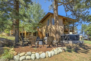 A lodge with a patio area featuring Adirondack chairs, a table, and a hot tub. - Highland Retreat (Woodland Park)