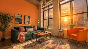 A living room with a green sofa, a wooden coffee table, and a vibrant rug.