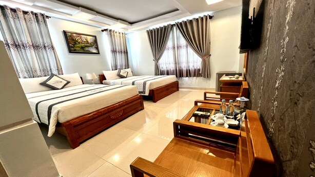 Quarto de hotel com duas camas, uma televisão, uma mesa de centro de madeira e um quadro na parede.