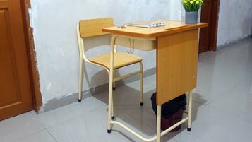 A wooden desk with a chair, a notebook, and a potted plant.