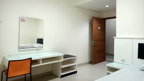 Habitación de hotel con un lavamanos blanco, espejo, una silla anaranjada, armario de madera y una cama.