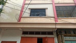 Un edificio con una puerta grande naranja, una ventana con celosía metálica y un letrero con el número 971.