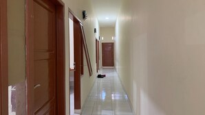 Un pasillo con puertas de madera, piso de baldosas y un aplique en la pared.