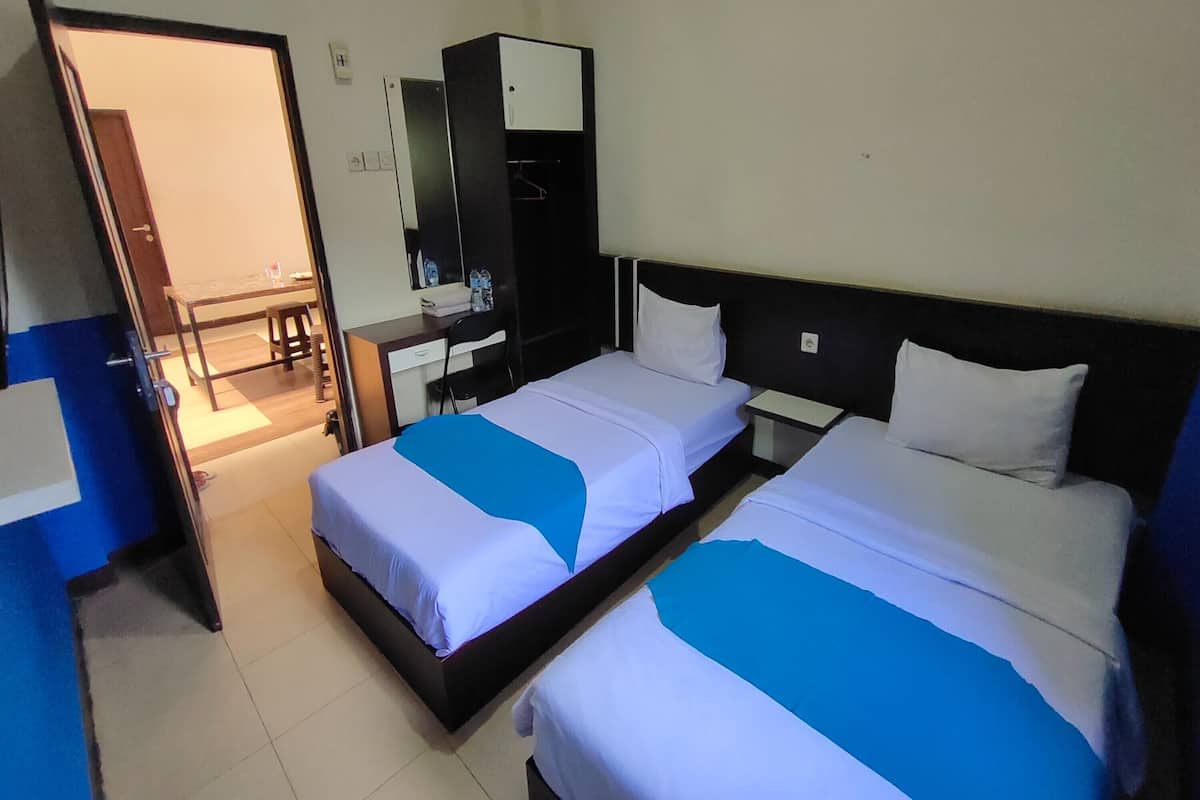 Ein Hotelzimmer mit zwei Betten, einem Schreibtisch und einem Kleiderschrank.
