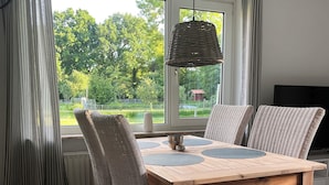 Un comedor con una mesa de madera, sillas de mimbre y una lámpara colgante.