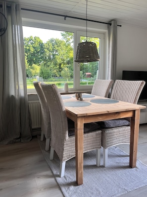 Et spiseområde med et træbord, fletstole og en hængende lampe.