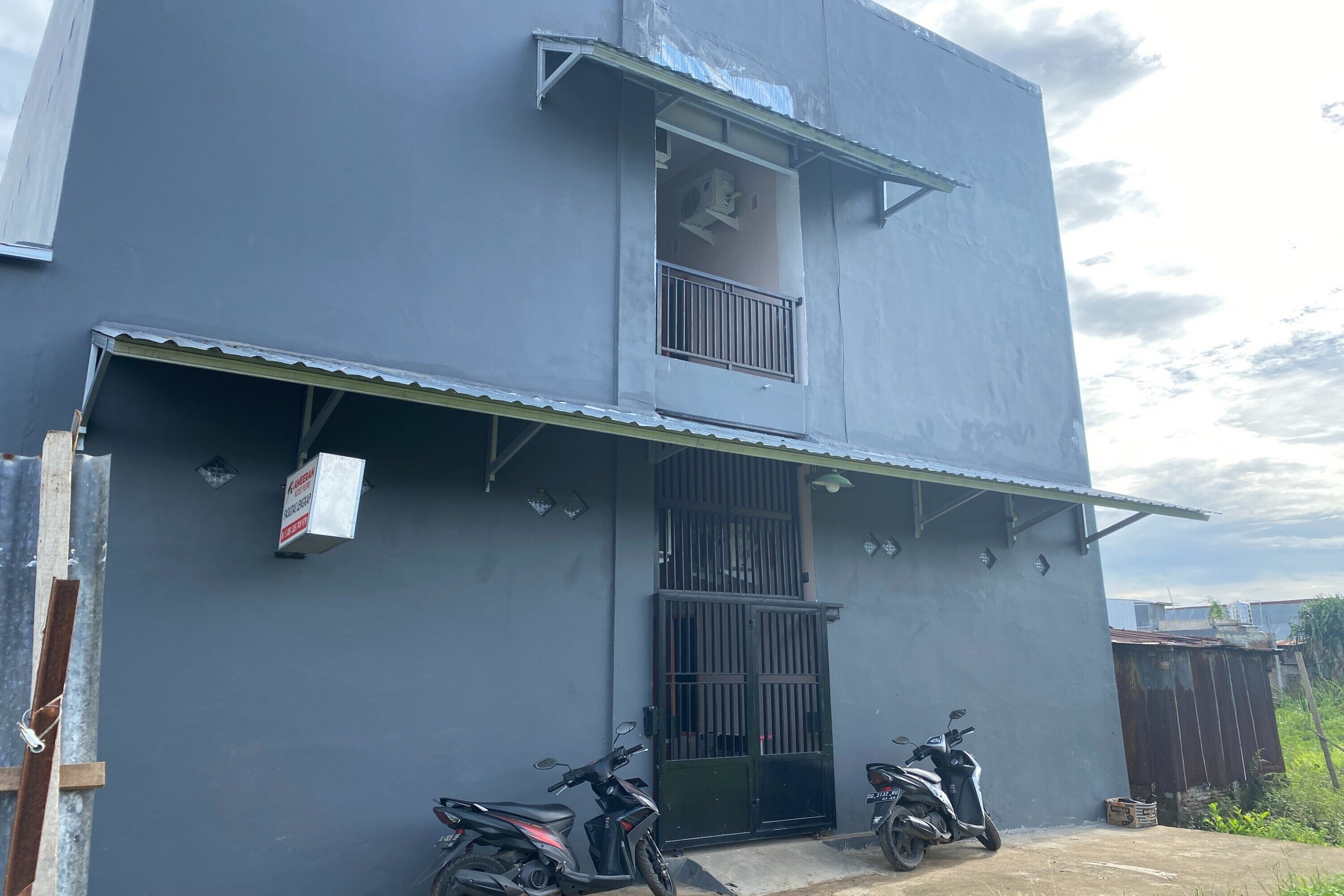 Un edificio de dos pisos con balcón y entrada protegida por reja.