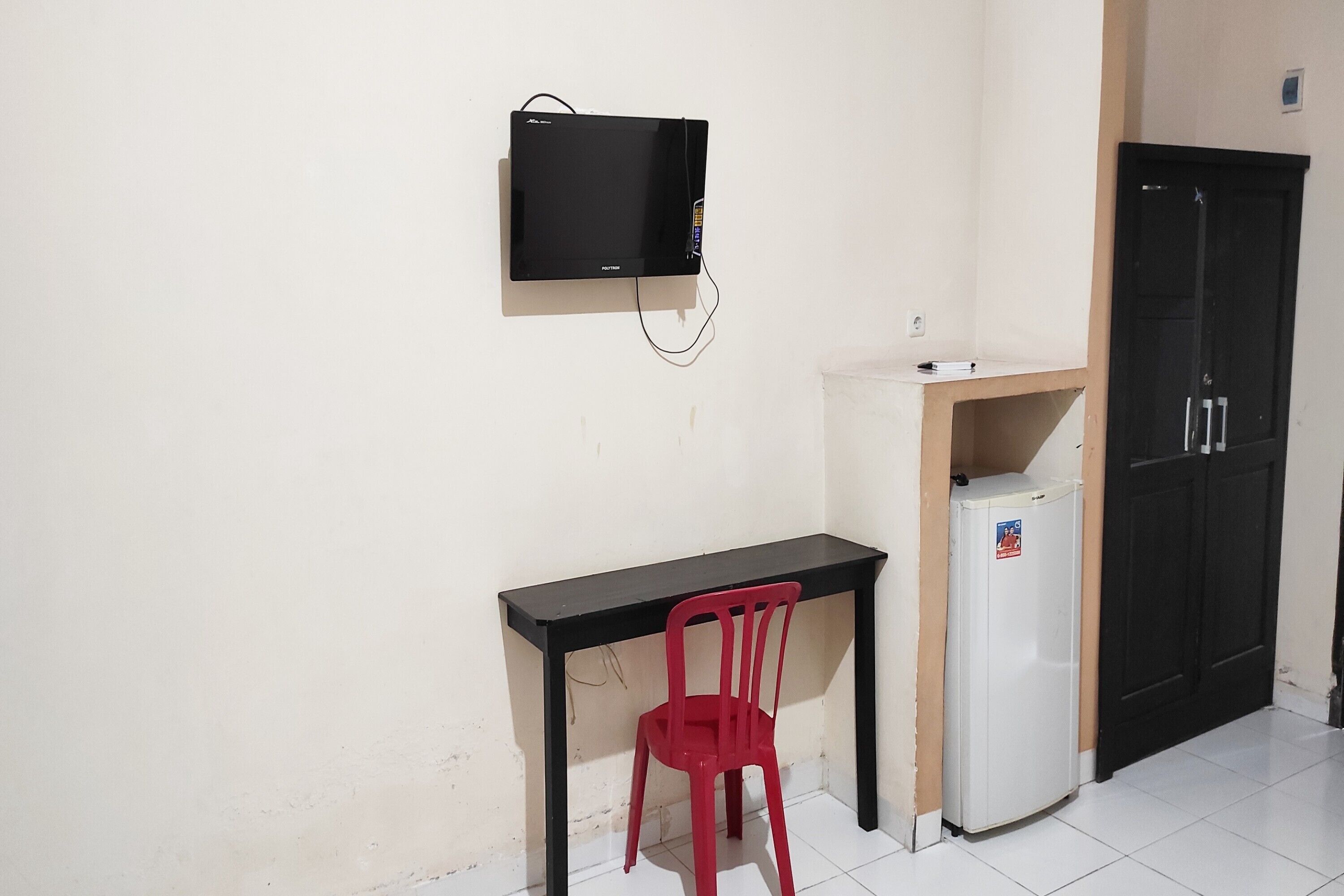 A small kitchenette with a black microwave, a red chair, and a white refrigerator.