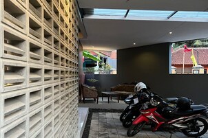 A modern interior with a motorcycle parked near a wall with a grid pattern.