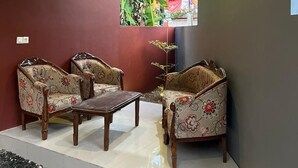 Un coin salon avec deux canapés et une table, adossé à un mur rouge et offrant une vue sur l’extérieur par une fenêtre.