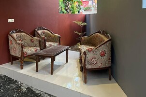 A seating area with two sofas and a table, against a red wall with a window view.