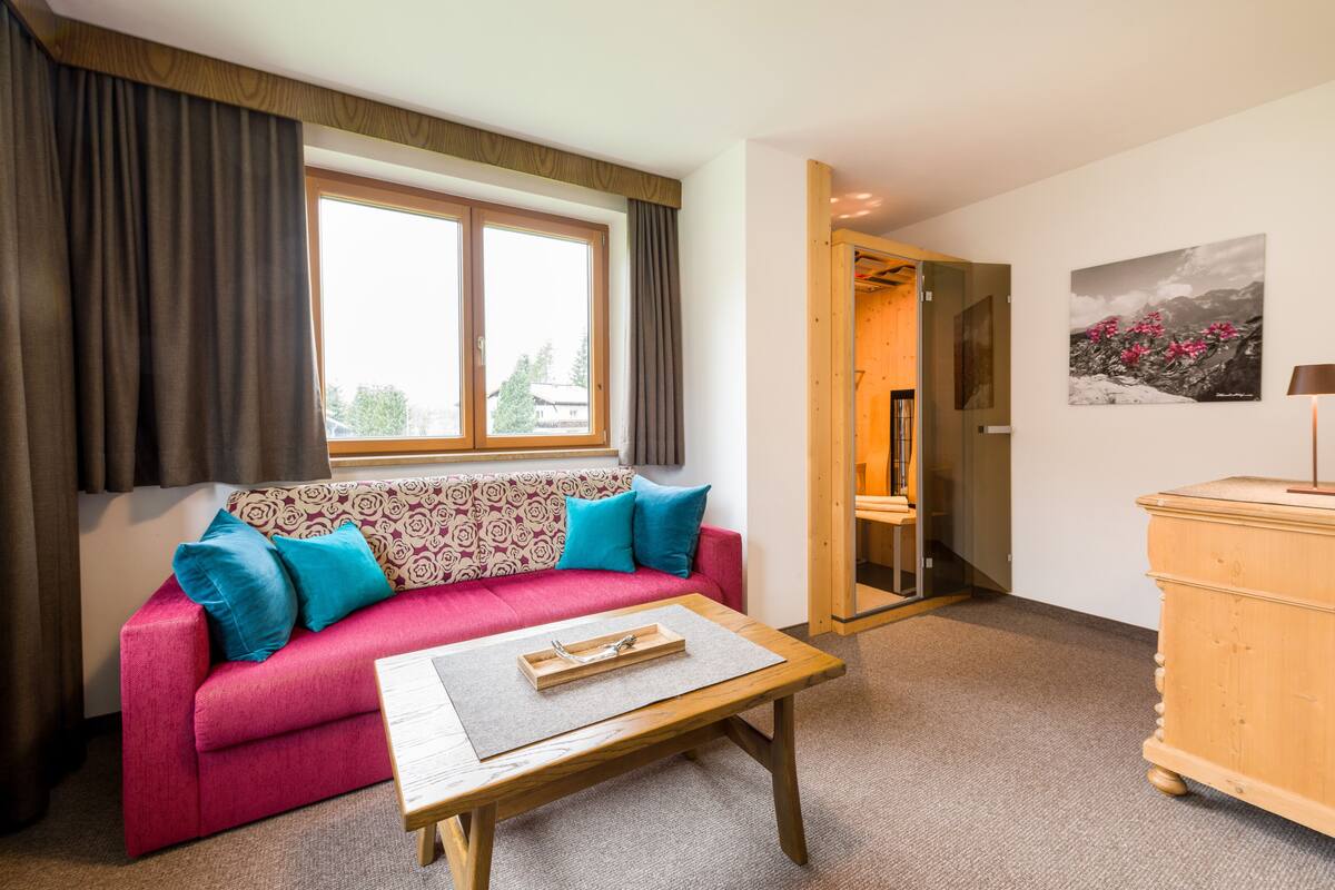A cozy room with a red sofa, a wooden coffee table, and a wooden dresser.