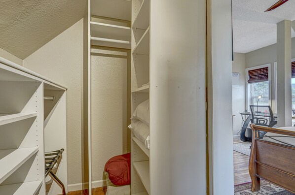 A walk-in closet with open shelving and a red chair.
