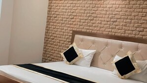 A bedroom with a brick-patterned headboard, a bed with white bedding, and two bedside tables with black screens. - King Palace By GRB (Agra)