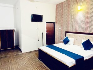 A bedroom with a bed, a television, a wardrobe, and a patterned wall. - King Palace By GRB (Agra)