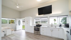 Een moderne keuken met witte kasten, een ingebouwde oven en een groot raam.