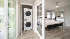 Een slaapkamer met een bed, een plafondventilator en een wasmachine in een wasruimte.