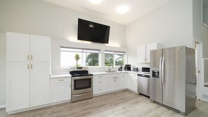 Een moderne keuken met witte kasten, roestvrijstalen apparatuur en een groot raam dat voor natuurlijk licht zorgt.