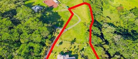 An aerial view of a property with a large green field, a small building, and a winding road.