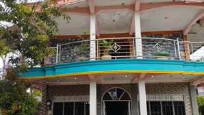 A two-story building with a balcony, a stone wall, and a tiled entrance. - Hotel O Losmen Karunia Katingan Near Kantor Sekretariat PPK Katingan Kuala (Pegatan Hilir)