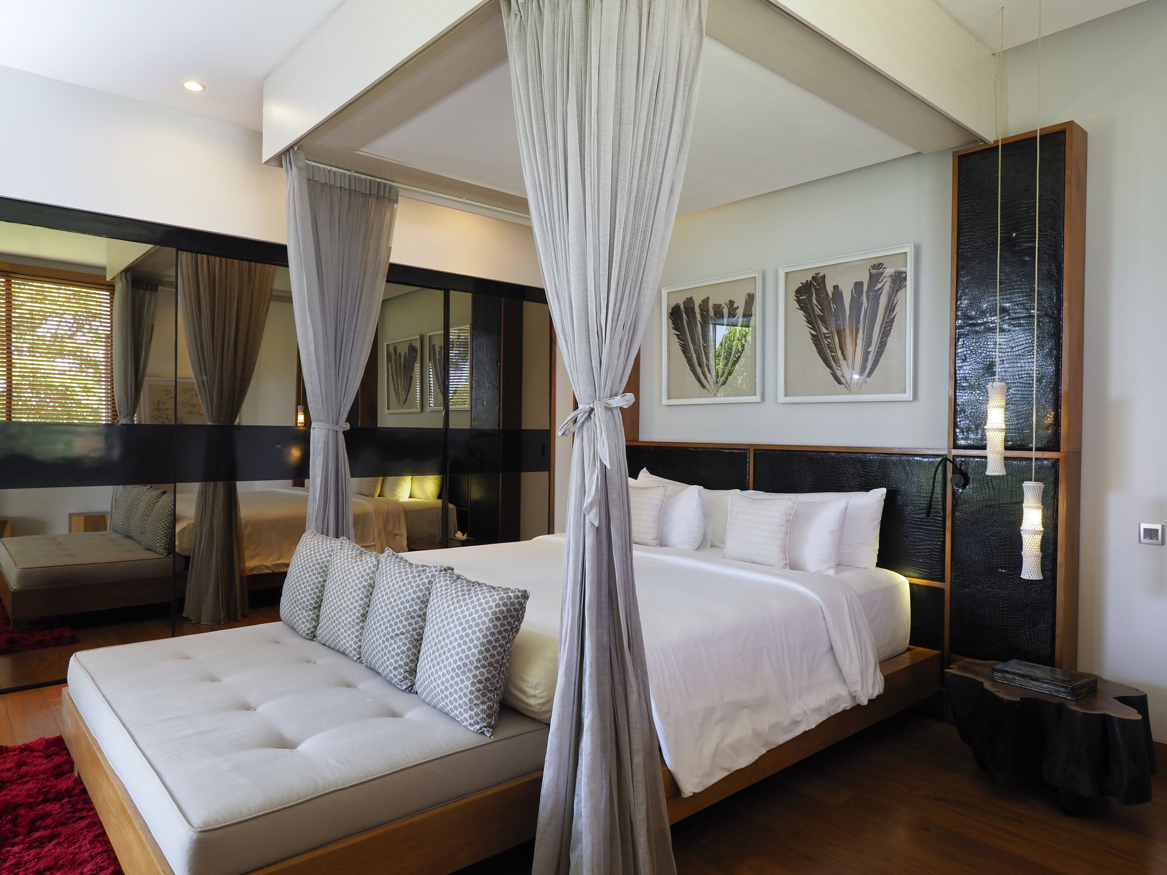 A spacious bedroom with a large bed, a sitting area, and a mirror.