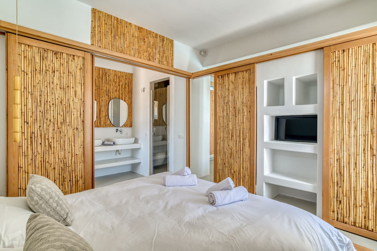 A modern hotel room with a large bed, a bathroom with a vanity, and a television mounted on the wall.