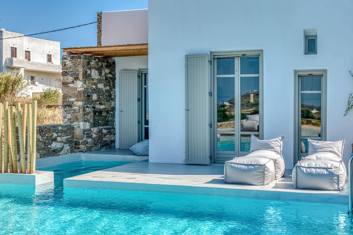 A modern pool area with a stone wall and a white building with large windows and a door.