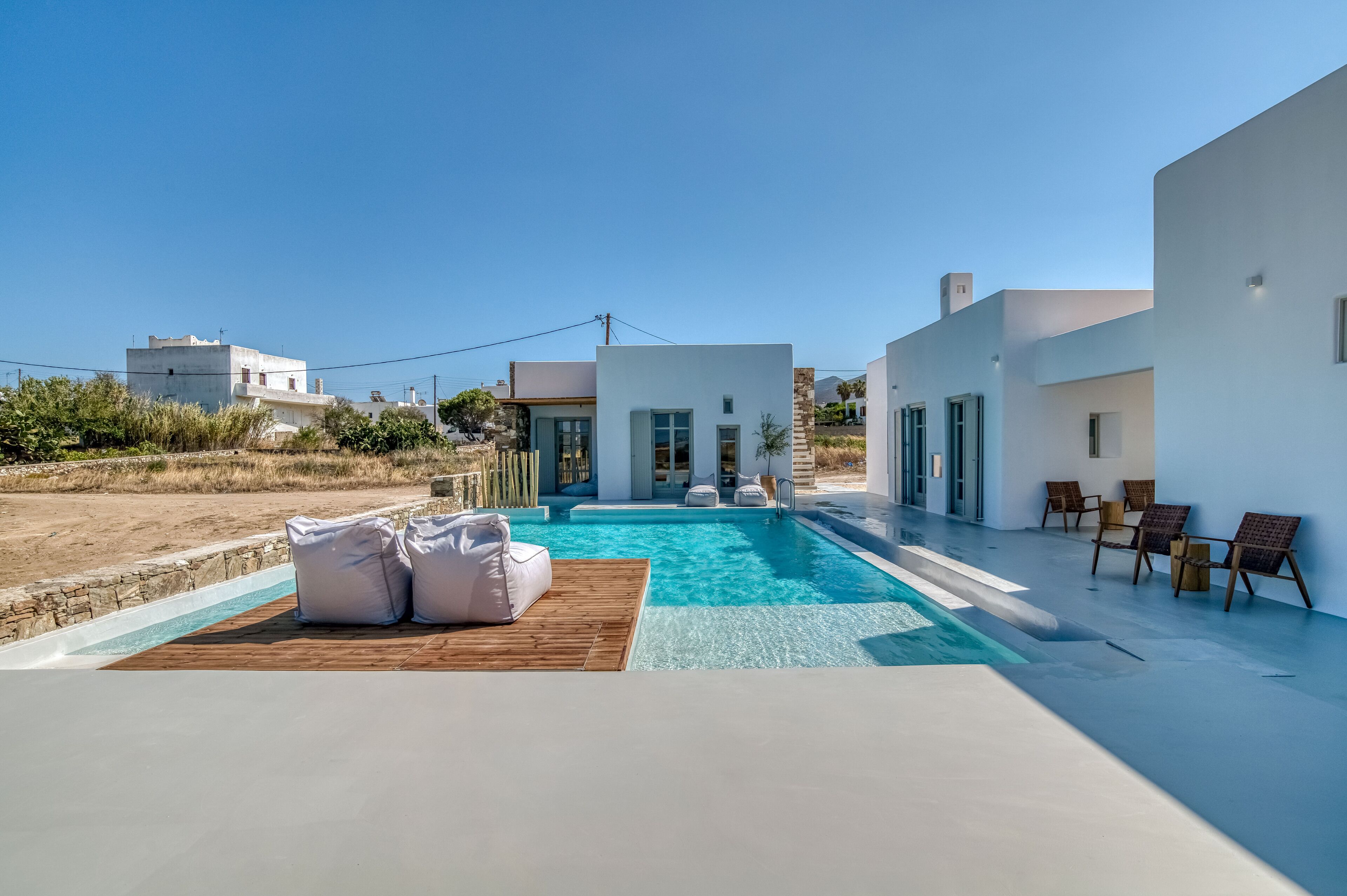 A modern pool area with a clear blue pool, white walls, and a wooden deck.