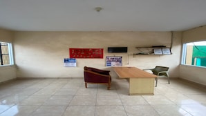 A room with a wooden table, a red sofa, a green chair, and a TV on the wall. - OYO 93518 Kepayang Guesthouse Syariah (Bandar Lampung)