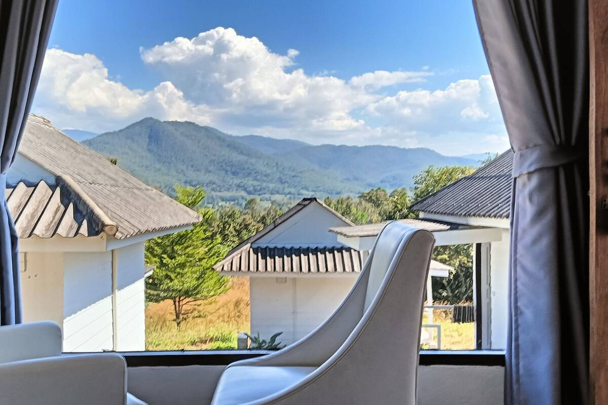 Una habitación con vistas a montañas y casas tradicionales.